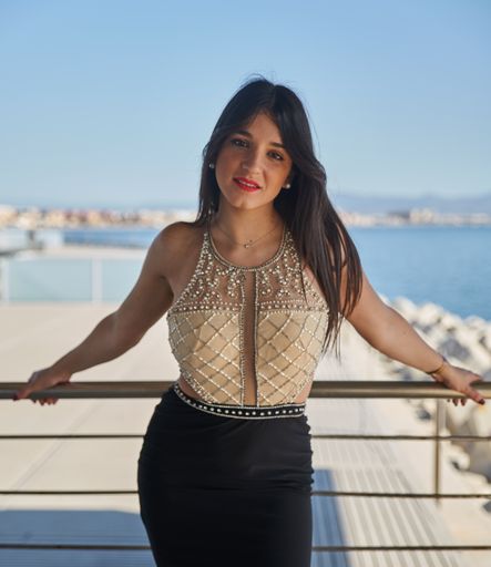 A Caucasian woman wearing an evening dress and posing near the sea