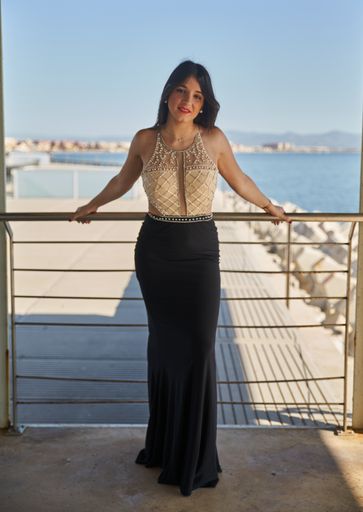 A vertical shot of a Caucasian woman wearing en evening dress and posing