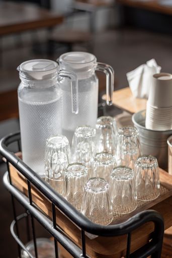 A vertical selective focus shot of glass water pitchers and empty upside-down glasses on a tray