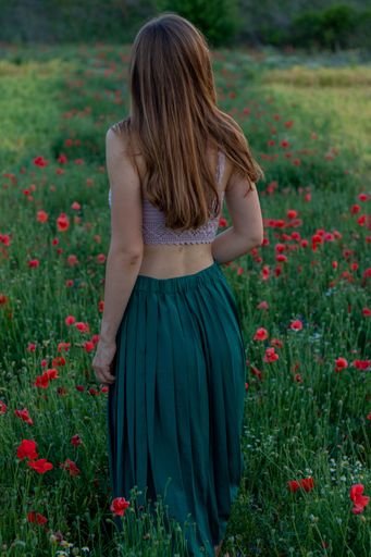 A tranquil vertical shot of a girl in the green poppy field
