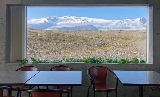A room with big window showing snowy mountains and a glacier in Iceland