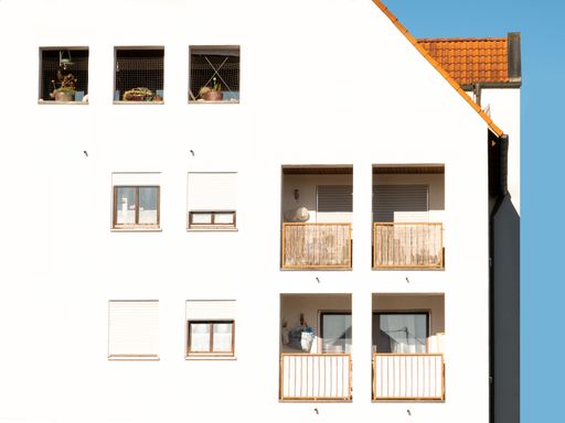 A modern white concrete building with a multitude of windows spanning its surface
