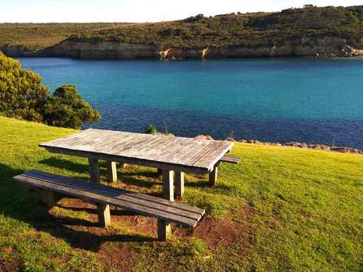 A wooden table with benches, a perfect place to enjoy the warm sunshine and the stunning blue water