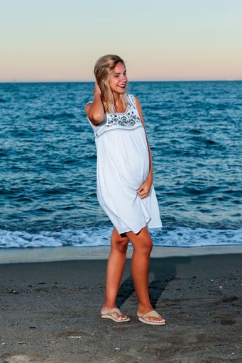 A vertical shot of a Hispanic pregnant woman on the beach at sunset