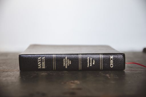 A closeup shot of the bible on a wooden surface with a blurred background