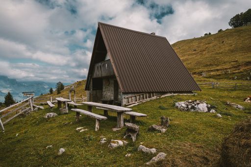 A closeup shot of a brown hut in a meadow with a bench on the front