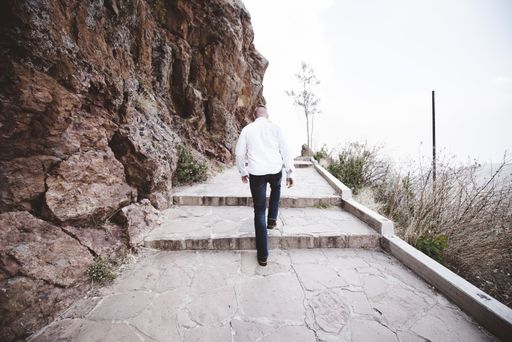 A male walking up the pathway on the side of a mountain shot from behind