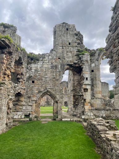 A vertical shot of the ancient Roman Ruins of a building with archways under a gloomy gray sky