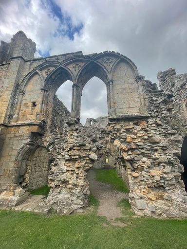 A vertical shot of the ancient Roman Ruins of a building with archways and brick columns under a bright cloudy sky