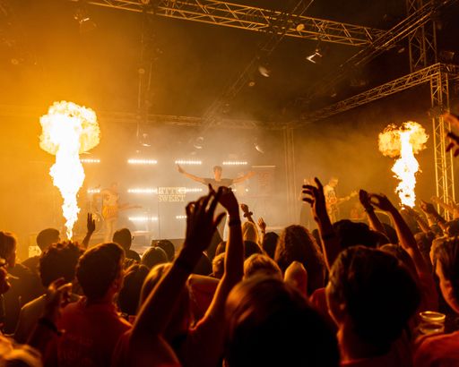A concert with flamethrowers and a large crowd of dancing people