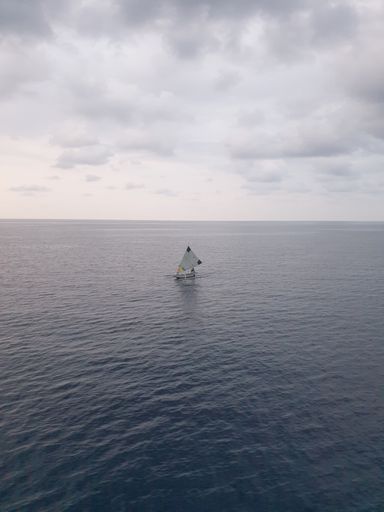 A vertical shot of a ship sailing on the beach