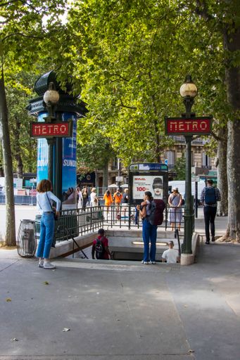 Paris, France - Friday 29th July 2022: entrance of metro station with art deco metro signs on the lamp posts. High quality photo