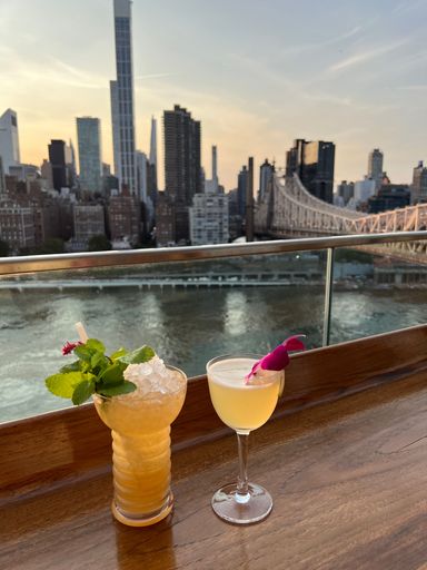 Two glasses of cocktails with a beautiful cityscape in the background