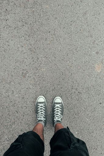 A top-view shot of a man wearing grey sneakers standing on a ground