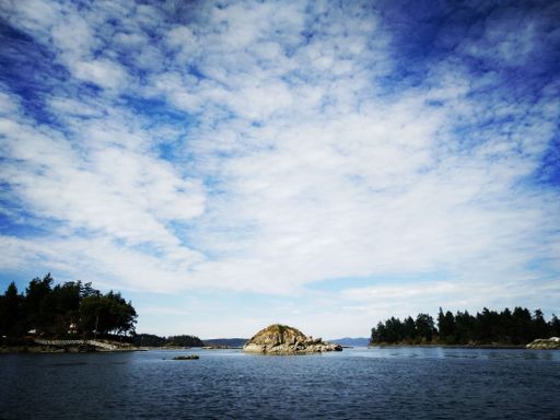 A rocky islet in the blue sea under blue cloudy sky