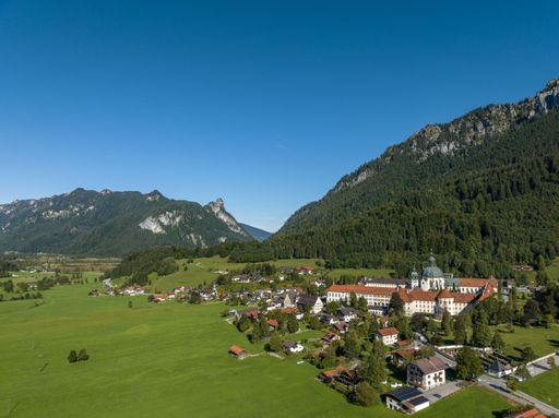 An aerial shot of Ettal Germany surrounded by green fields and scenic mountains