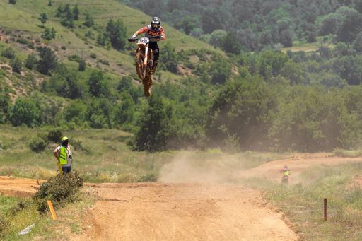 A scenic view of a biker doing a jump during a Motocross race in a mountainous area