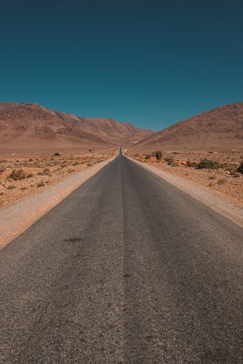A vertical shot of a road in the middle of the desert and mountains captured in Morocco