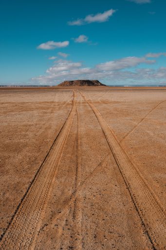 A vertical shot of tire tracks on the desert under the blue sky captured in Morocco