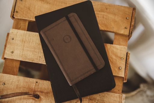 An overhead shot of a notebook on the bible on a wooden box with a blurred background