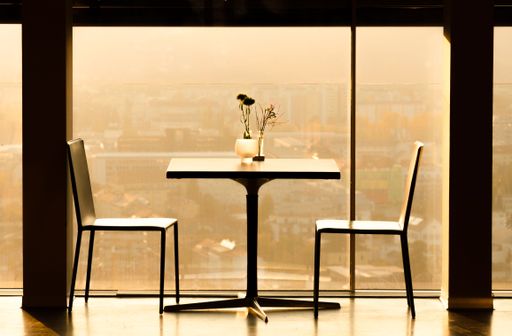 A minimalistic interior of cafe table and two chairs next to window in brown color  effect