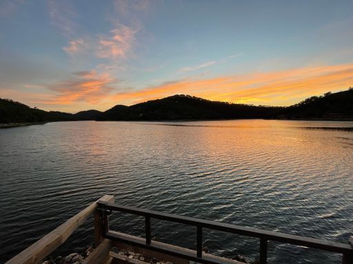 A beautiful shining golden, orange sunset reflected on surface of undulating lake on summer evening