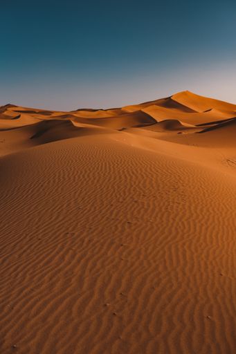 A vertical shot of a peaceful desert under the clear blue sky captured in Morocco