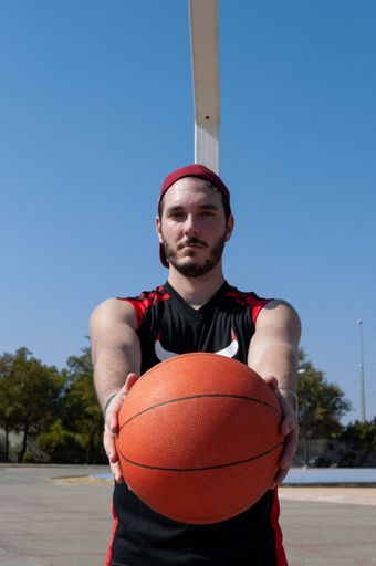 A vertical shot of a Caucasian male holding a basketball ball