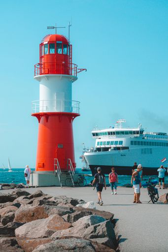 A vertical shot of a cargo ship and lighthouse