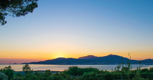 A scenic view off a sunset over the hills with a lake and greenery around
