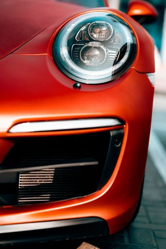 A vertical shot of the headlight of a red Porsche 911 Carrera 4 GTS