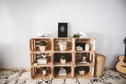 A closeup shot of a wooden shelf with plants and a sign on top of it