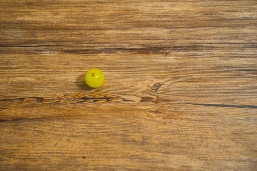 A top view of a yellow grape on a wooden table.