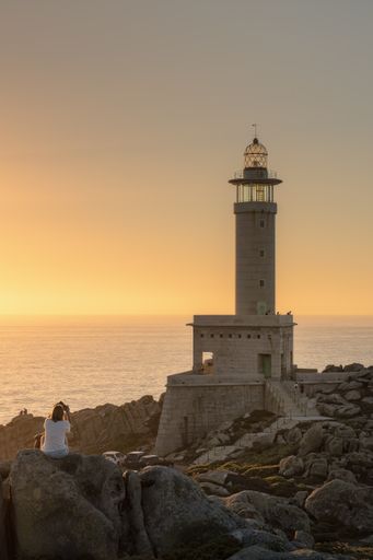 Tourists observe the Punta Nariga lighthouse, the most modern in Galicia, during the sunset.