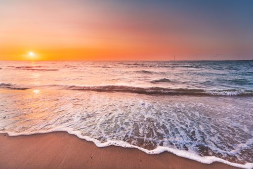 A beautiful view of the ocean waves coming to the shore under the sunset in Zeeland, Netherlands