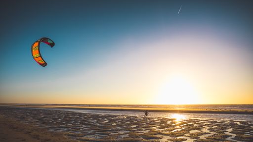A wide shot of a of a person kitesurfing by the beach captured at sunset in Oostkapelle, Netherlands