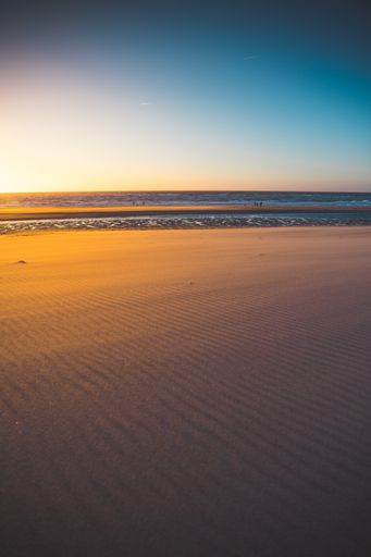A vertical shot of the beach and the sea under the sunset captured in Oostkapelle, Netherlands