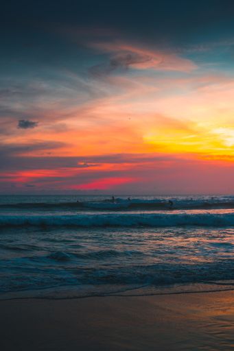 A vertical shot of the ocean waves under the colorful sky captured in Bali, Indonesia