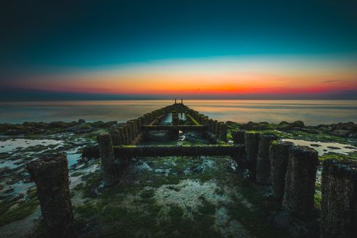 A moss covered wooden pier under the beautiful sky captured in Westkapelle, Netherlands