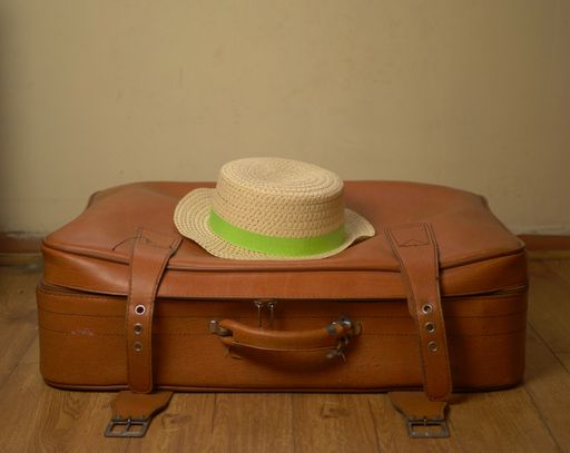 A closeup shot of a brown suitcase with a straw hat