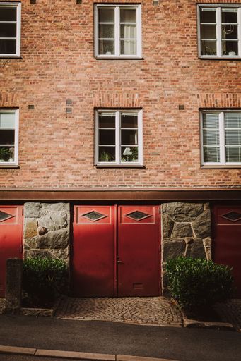 A vertical shot of a residential building facade with red garages