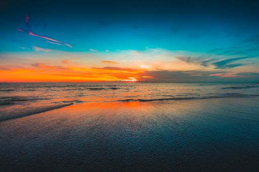 A beautiful view of the reflection of the sunset over the ocean under the cloudy sky captured in Bali