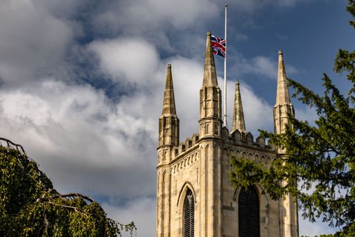 A low-angle shot of the Blackburn Cathedral with the United Kingdom flag on top on a sunny day