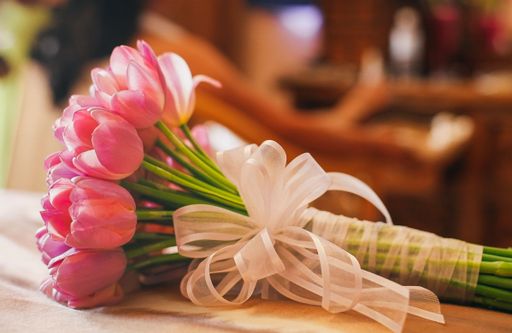 A closeup shot of pink tulips bouquet tied with a white elegant ribbon, the concept of present
