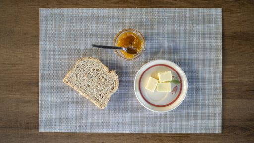 A top view of a slice of bread with butter and jam on a napkin on the table