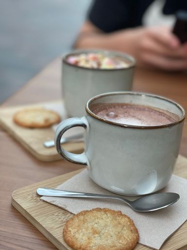 A closeup vertical shot of two cups of hot cappuccino on the wooden background