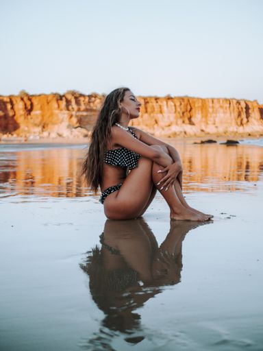 The attractive woman wearing  a bikini and posing for the camera at the beach