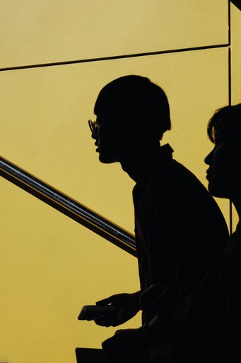 Silhouettes of people of Asian ethnicity looking at something with a yellow background