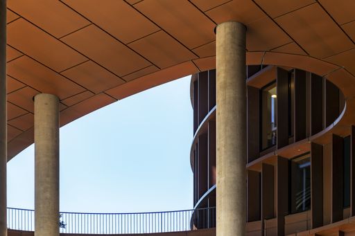 A low angle shot of a brown round-shaped  modern building with curvy twists under the clear sky