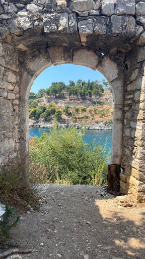 A vertical shot of a doorway of a medieval building with a river and a landscape in the background